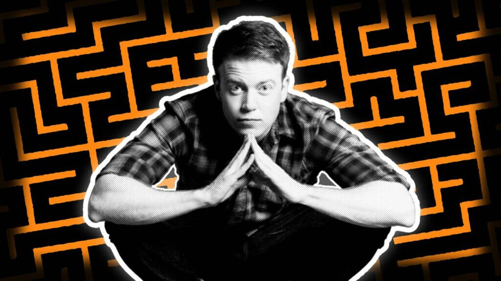 Brennan Lee Mulligan, an American actor and comedian, sits in front of a maze against an orange background.