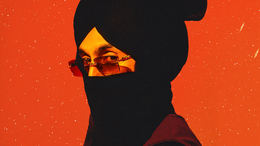 Singer Diljit Dosanjh posing on a plain orange background with sunglasses and a face covering.