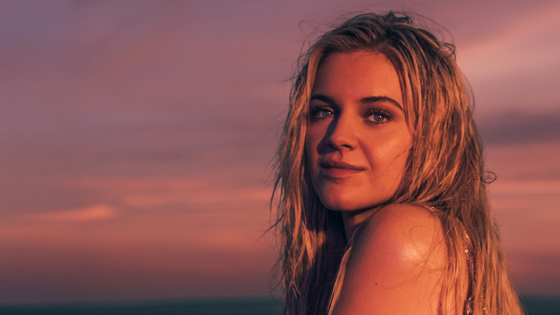 Singer Kelsea Ballerini posing on a beach.