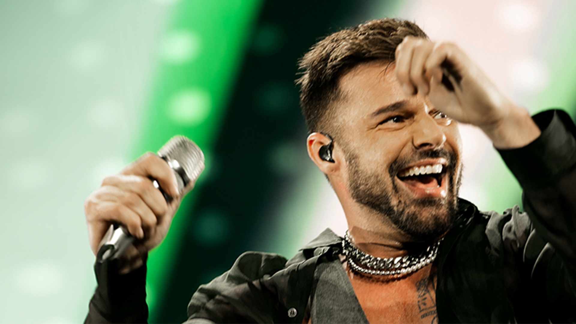Singer Ricky Martin dancing on stage with a microphone in hand.