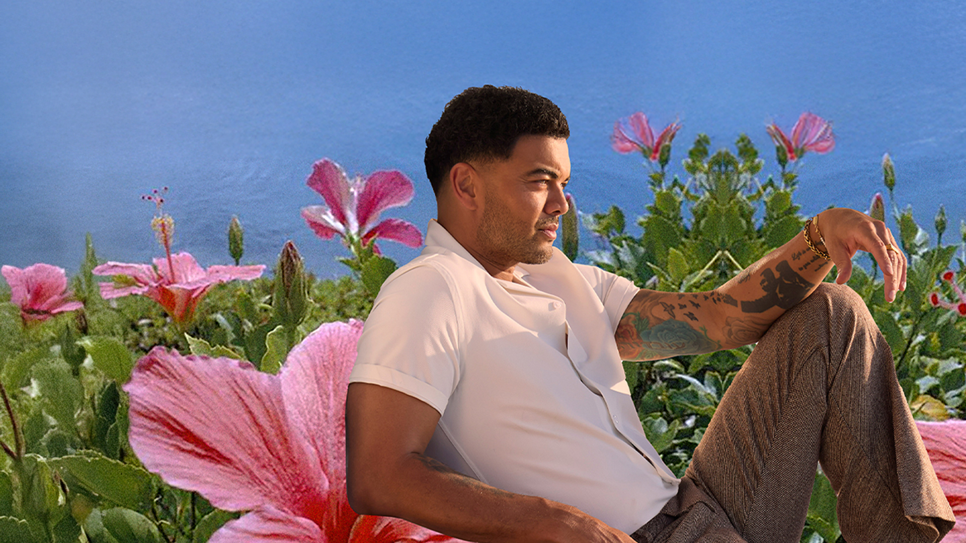 Guy Sebastian sitting and surrounded by colourful flowers, enjoying a peaceful moment outdoors.