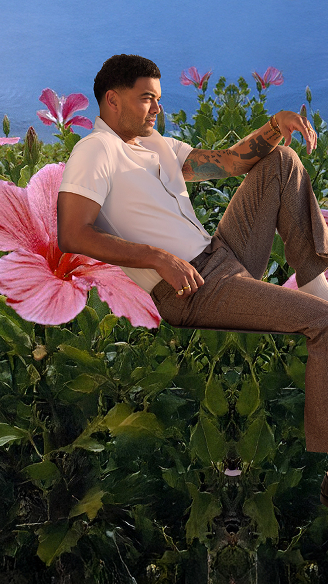Guy Sebastian sitting and surrounded by colourful flowers, enjoying a peaceful moment outdoors.