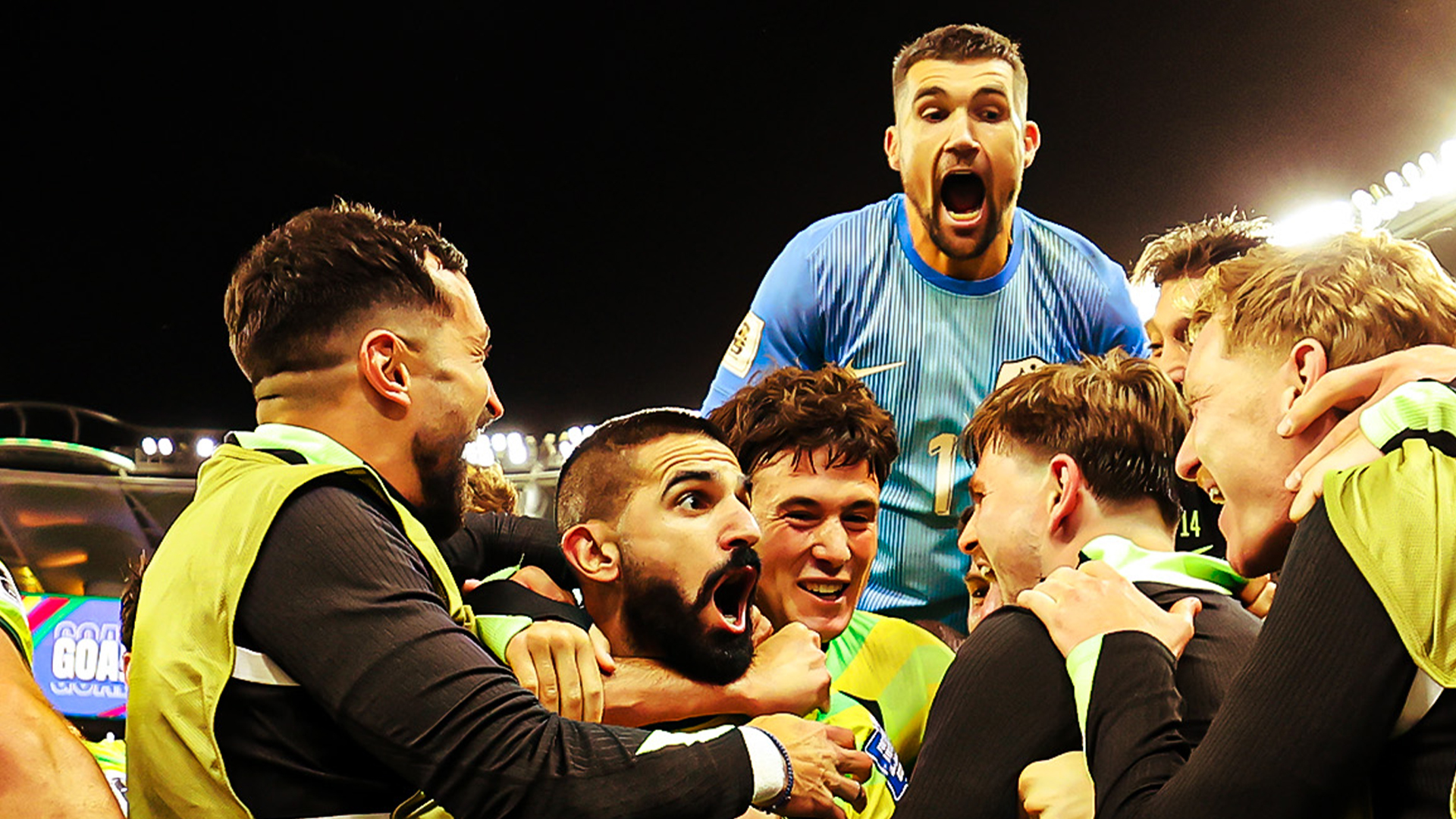 Socceroos footballers celebrating a soccer victory in a stadium.