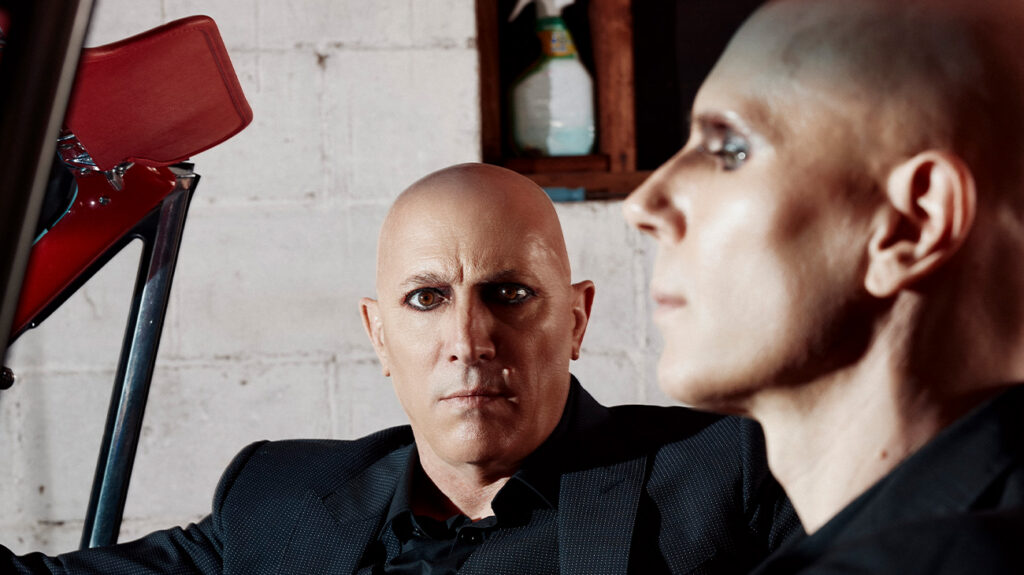 A Perfect Circle band members dressed in black and seated in a car.