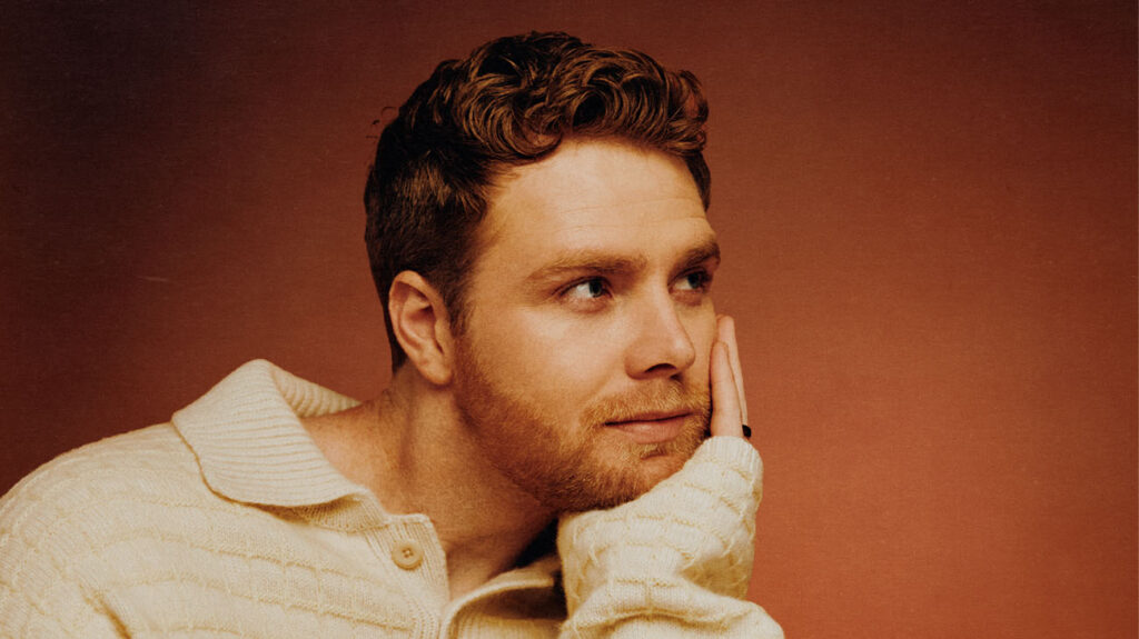 Alex Warren with head in hand gazing into the distance.