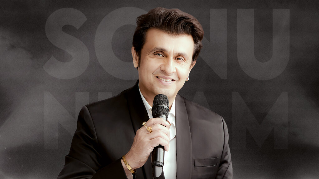 Sonu Nigam, holding a microphone and in a black suit, smiles in a promotional shot.