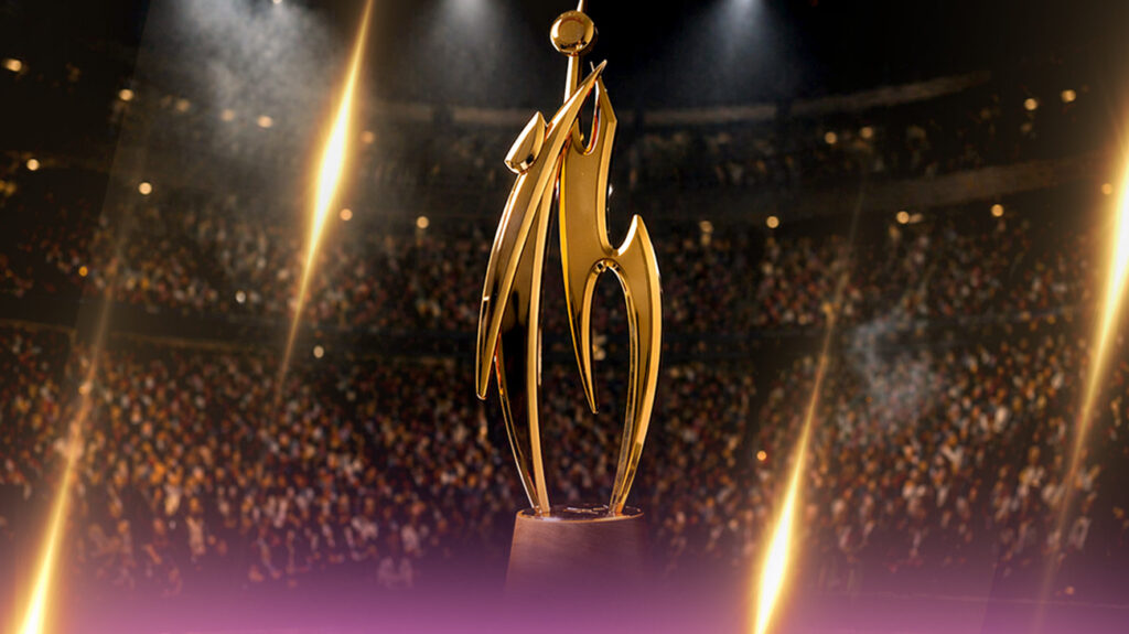 A golden trophy stands prominently in front of an arena crowd.