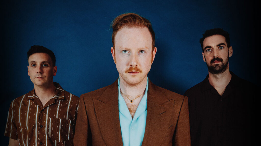 Two Door Cinema Club band members in suits, standing side by side, posing for the camera.