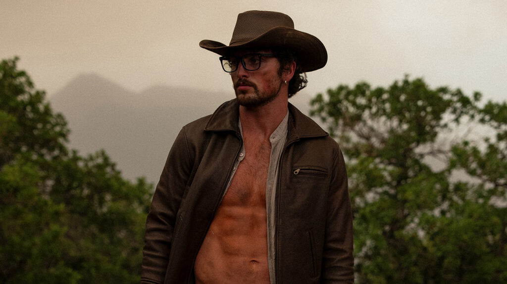 A shirtless Benson Boone wearing a cowboy hat and a jacket.