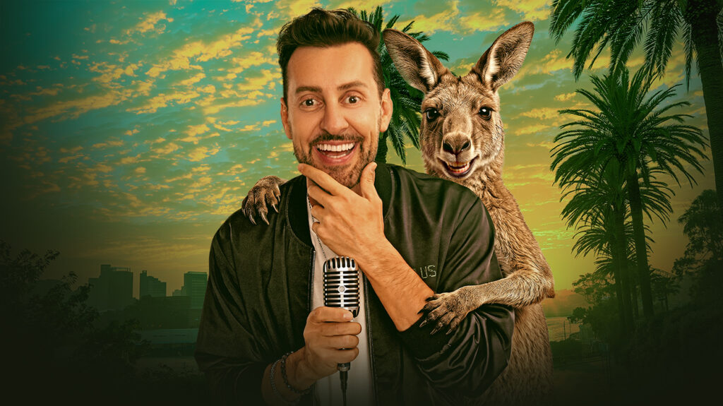 Max Amini holds a microphone while a kangaroo perches on his shoulder.