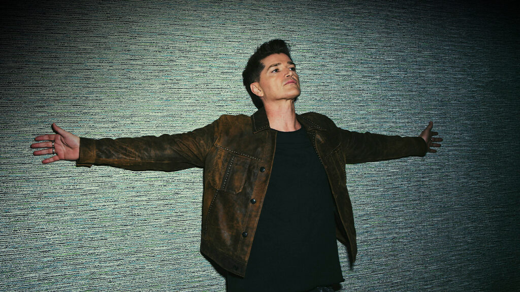 Lead singer of The Script band with arms spread and posing against a screen.