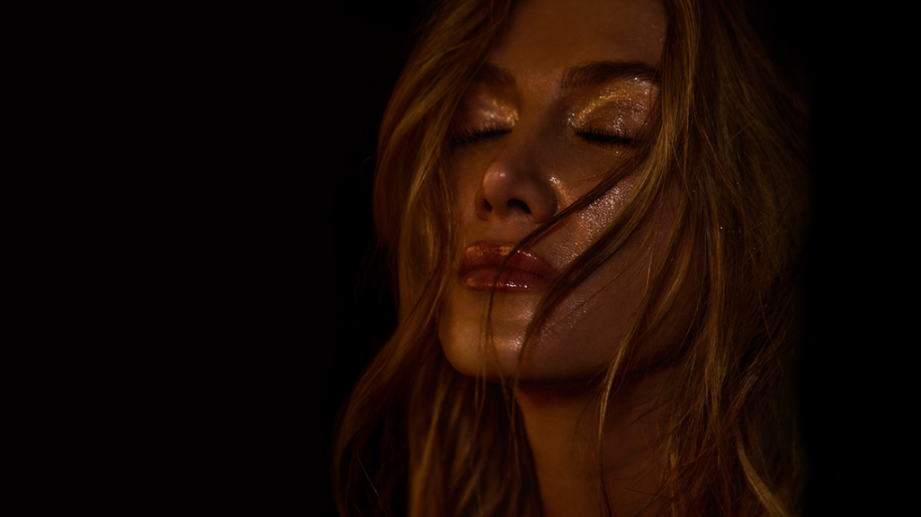 Delta Goodrem with closed eyes, flowing hair and a glittered face.