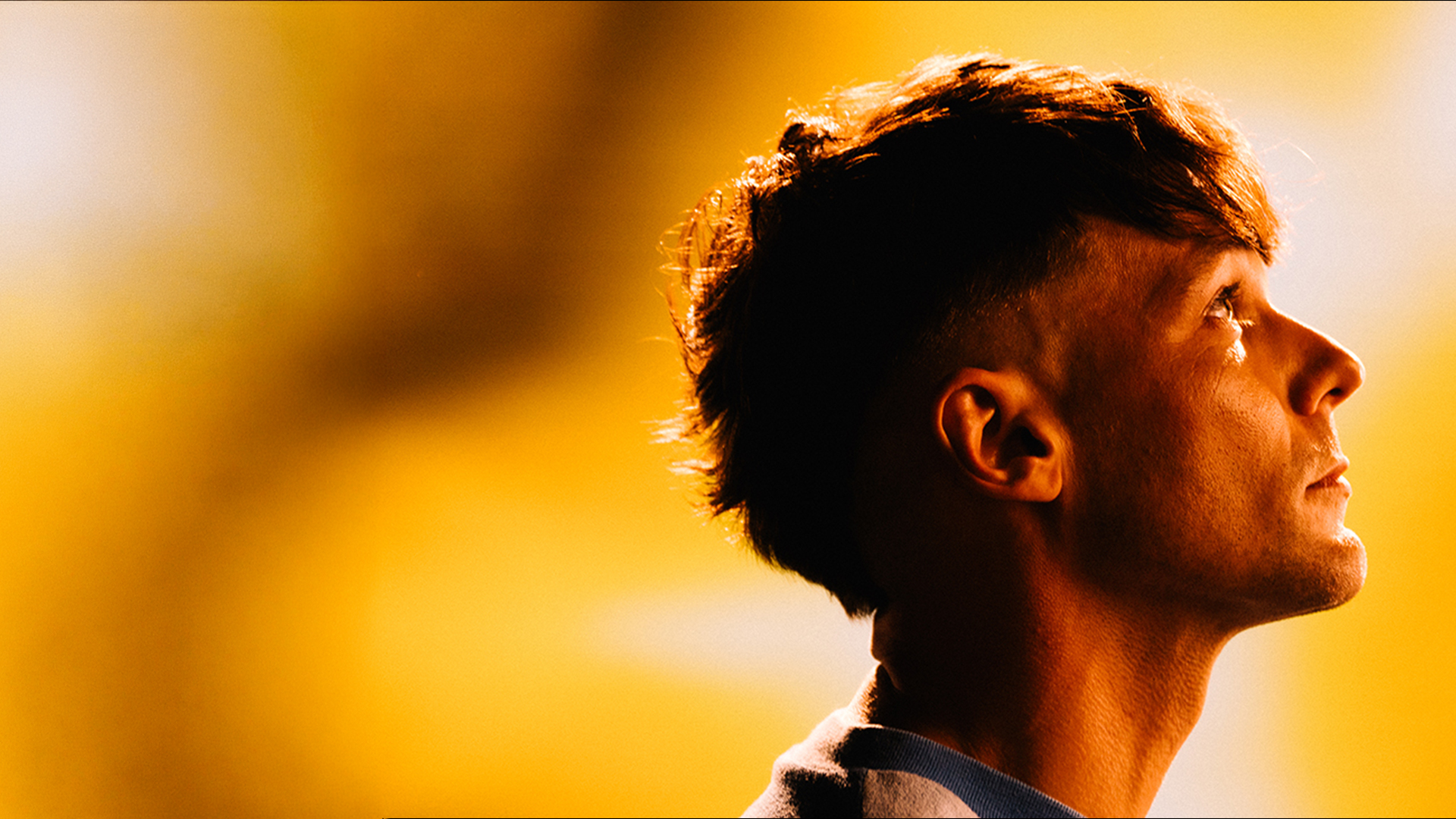 Louis Tomlinson, sporting short hair and a blue shirt, poses confidently for the photograph.