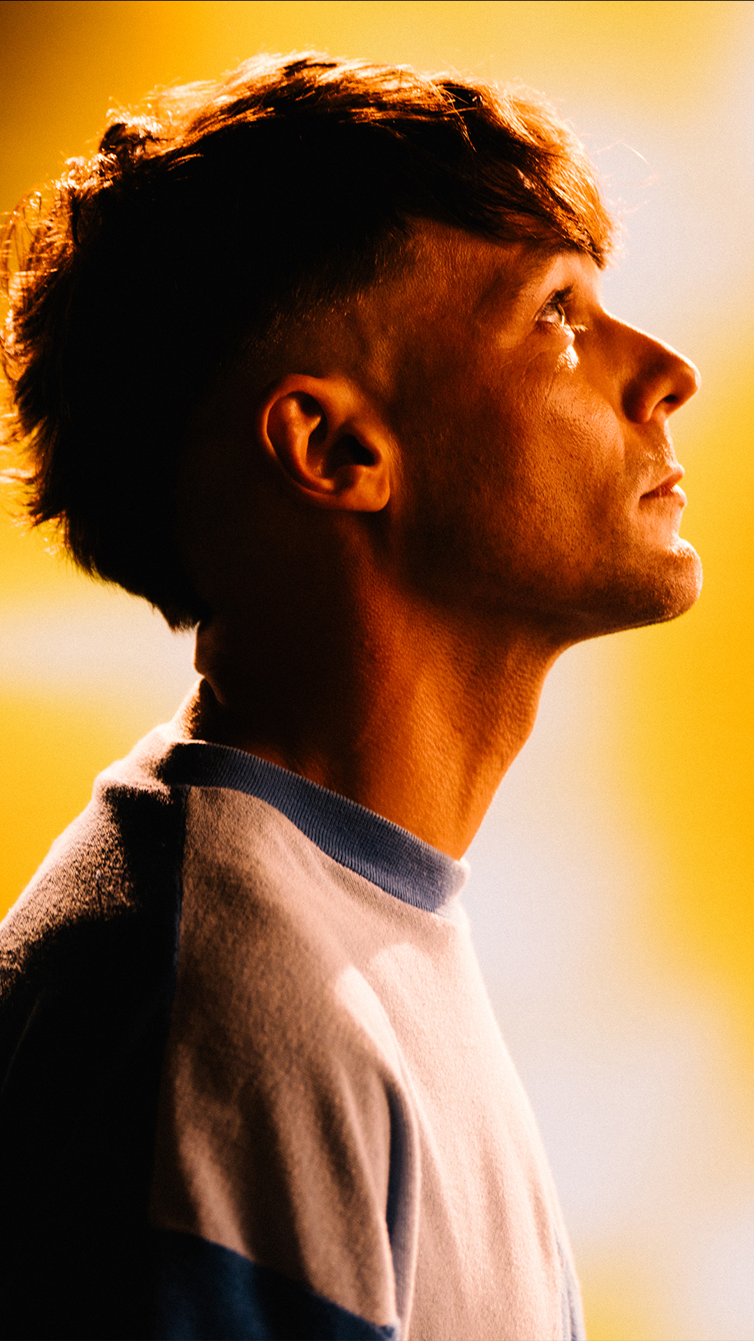 Louis Tomlinson, sporting short hair and a blue shirt, poses confidently for the photograph.