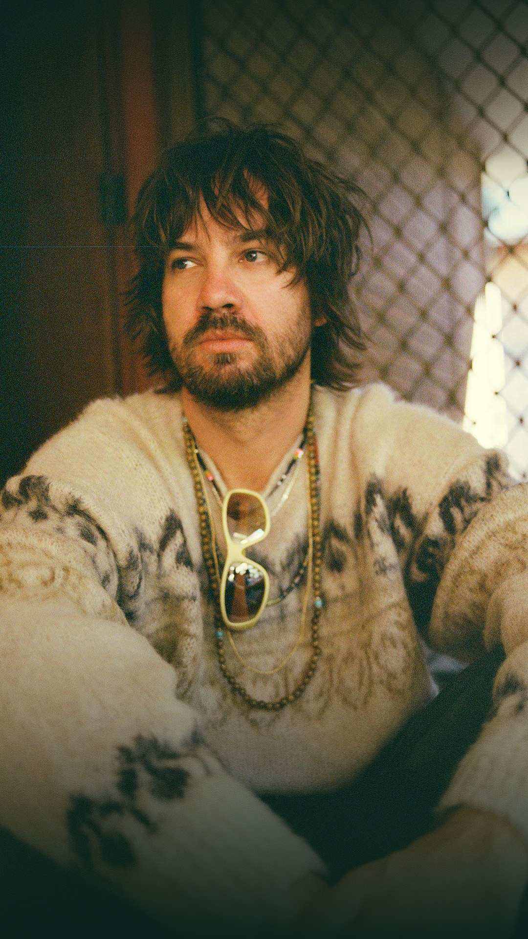 Australian musician Kevin Parker staring into the distance while sitting on a front porch.