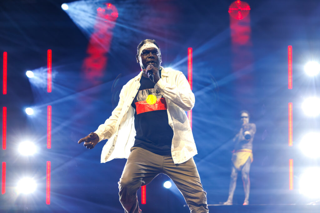 An Indigenous artist performing on stage during a concert.