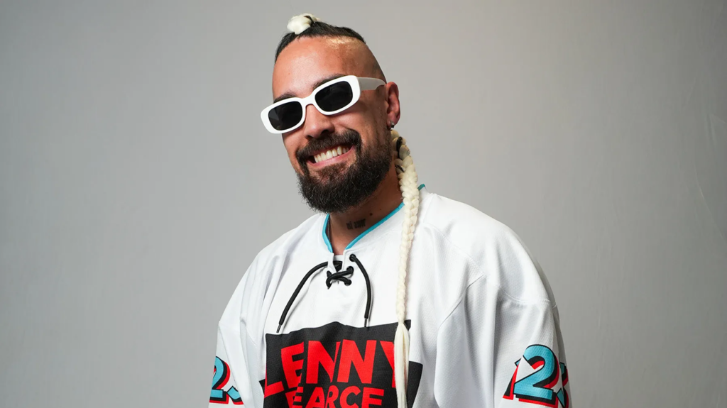 Lenny Pearce, a DJ with dreadlocks and sunglasses, poses against a neutral background.