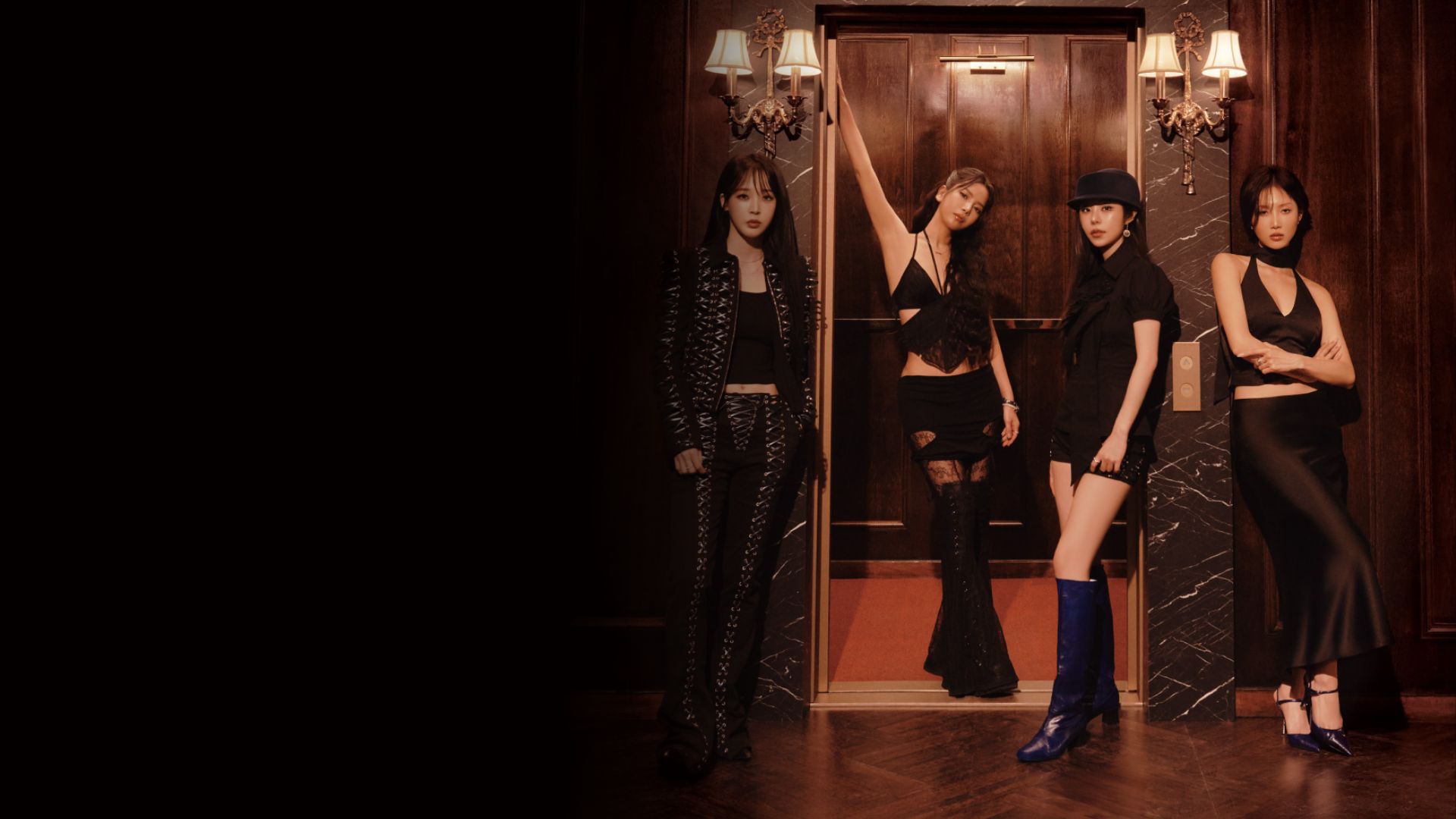 Mamamoo girl group members pose together, smiling at the camera in a vibrant setting.