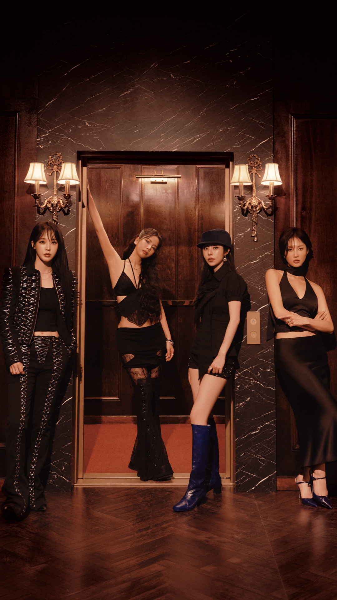 Mamamoo girl group members pose together, smiling at the camera in a vibrant setting.