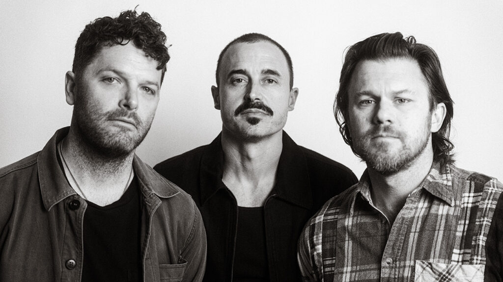 Three band members of The Fray pose in a black and white photo.