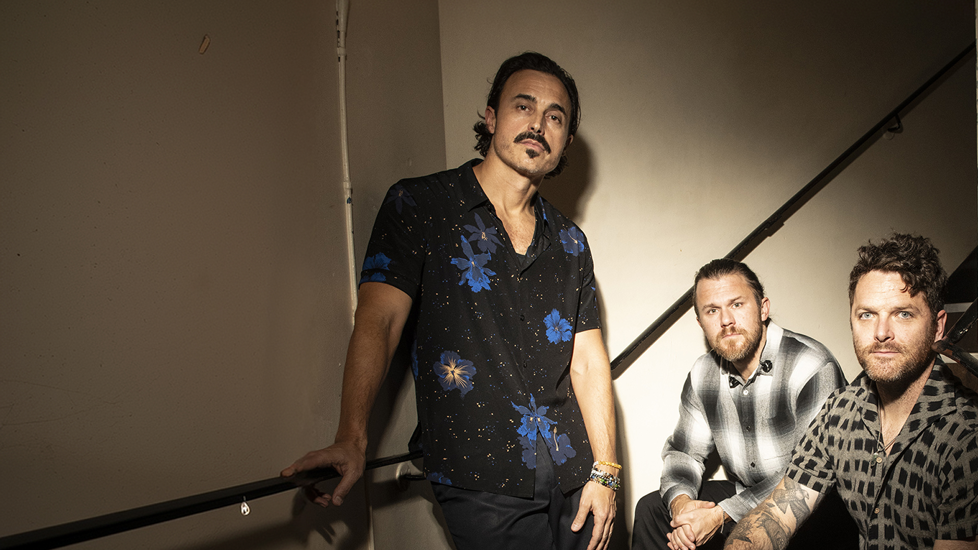 The Fray band members with serious poses against a stairwell.